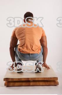Kneeling pose orange thsirt light blue jeans of bodybuilder Harold…